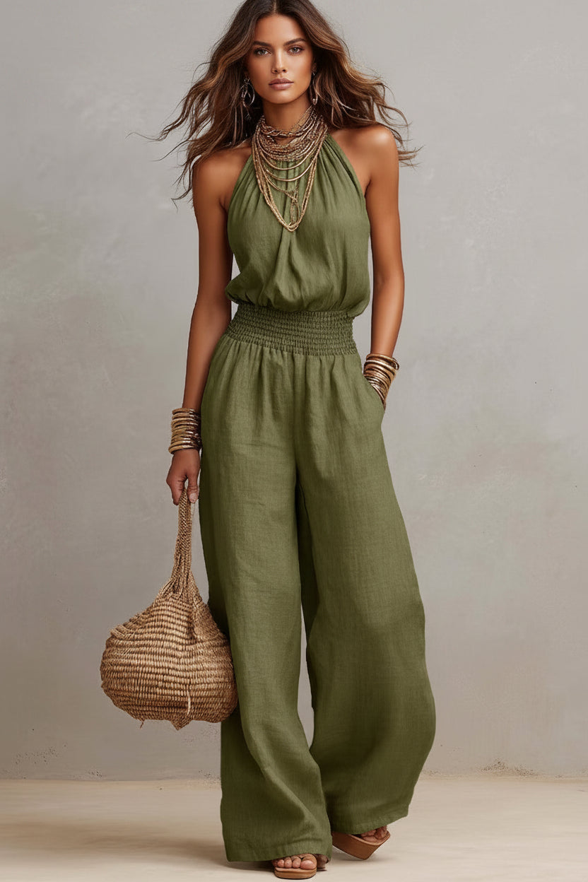 Woman wearing a green jumpsuit holding a woven bag against a neutral background