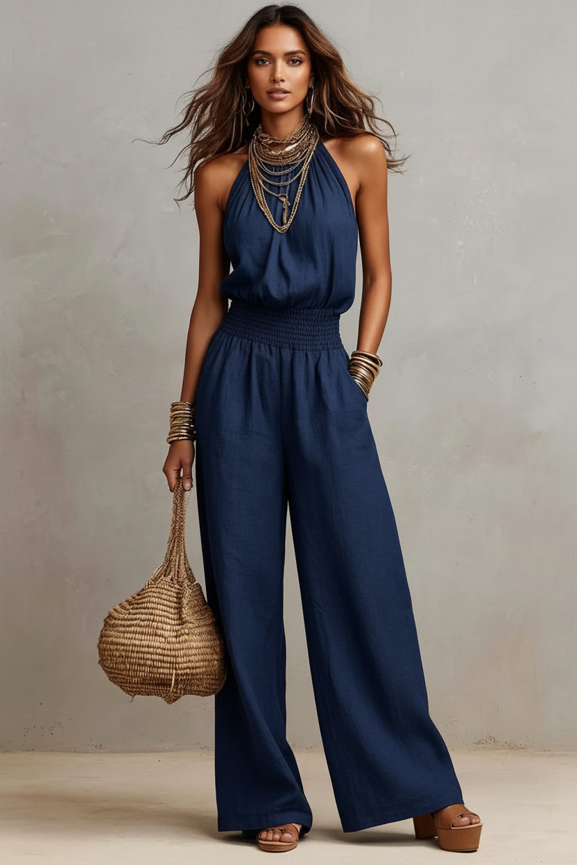 Woman wearing a blue jumpsuit holding a woven bag against a neutral background