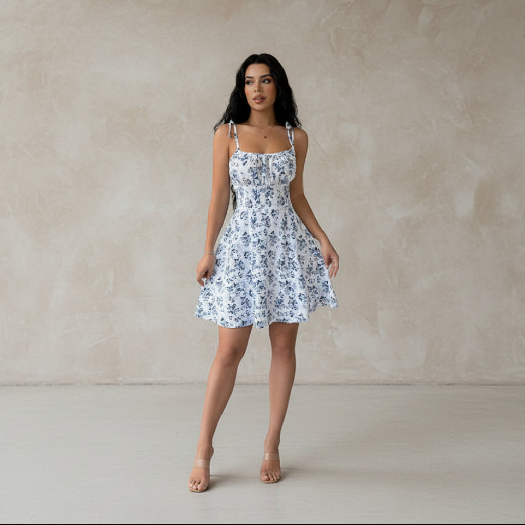 Woman wearing a white floral dress against a plain background