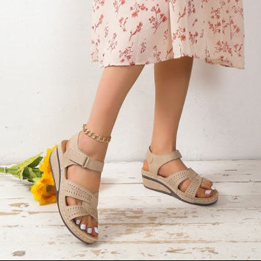 Person wearing a floral dress and beige sandals on a white background