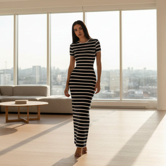 Person wearing a navy and white striped dress in a minimal indoor setting.