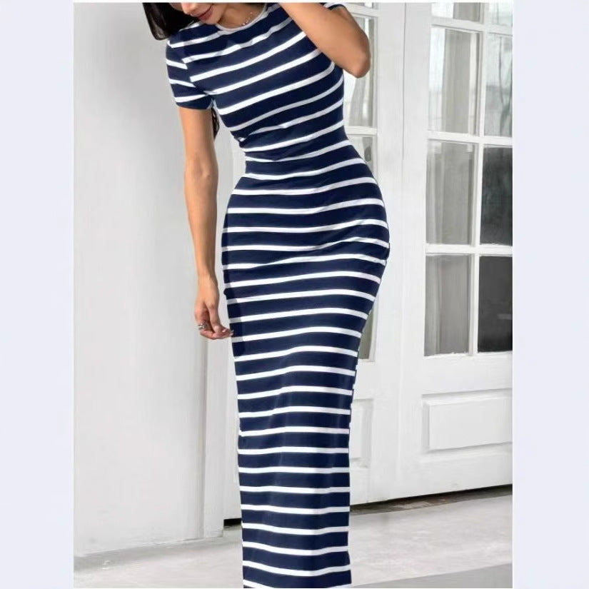 Person wearing a navy and white striped dress in a minimal indoor setting.