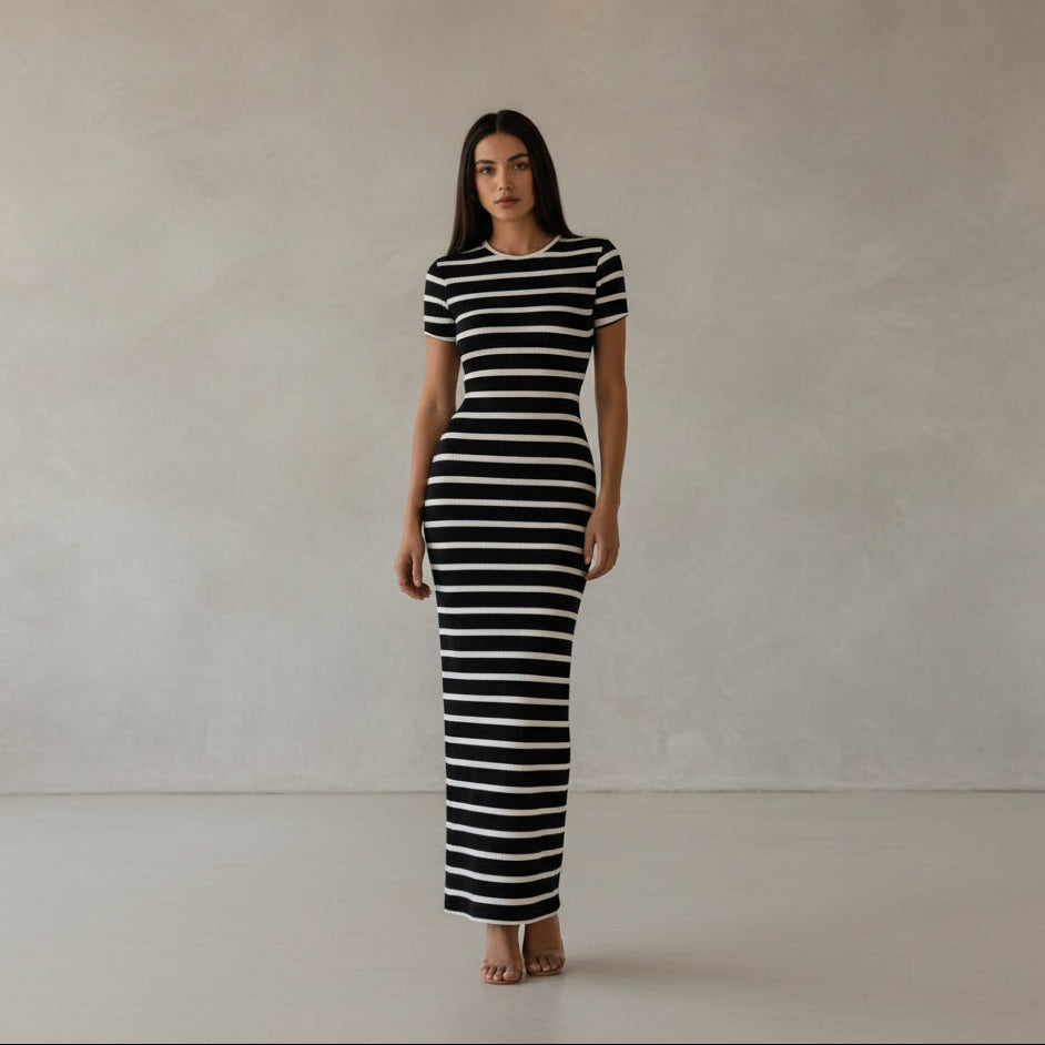 Person wearing a navy and white striped dress in a minimal indoor setting.