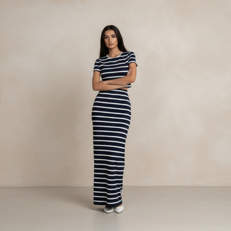 Person wearing a navy and white striped outfit with wide-leg pants in a minimal indoor setting.