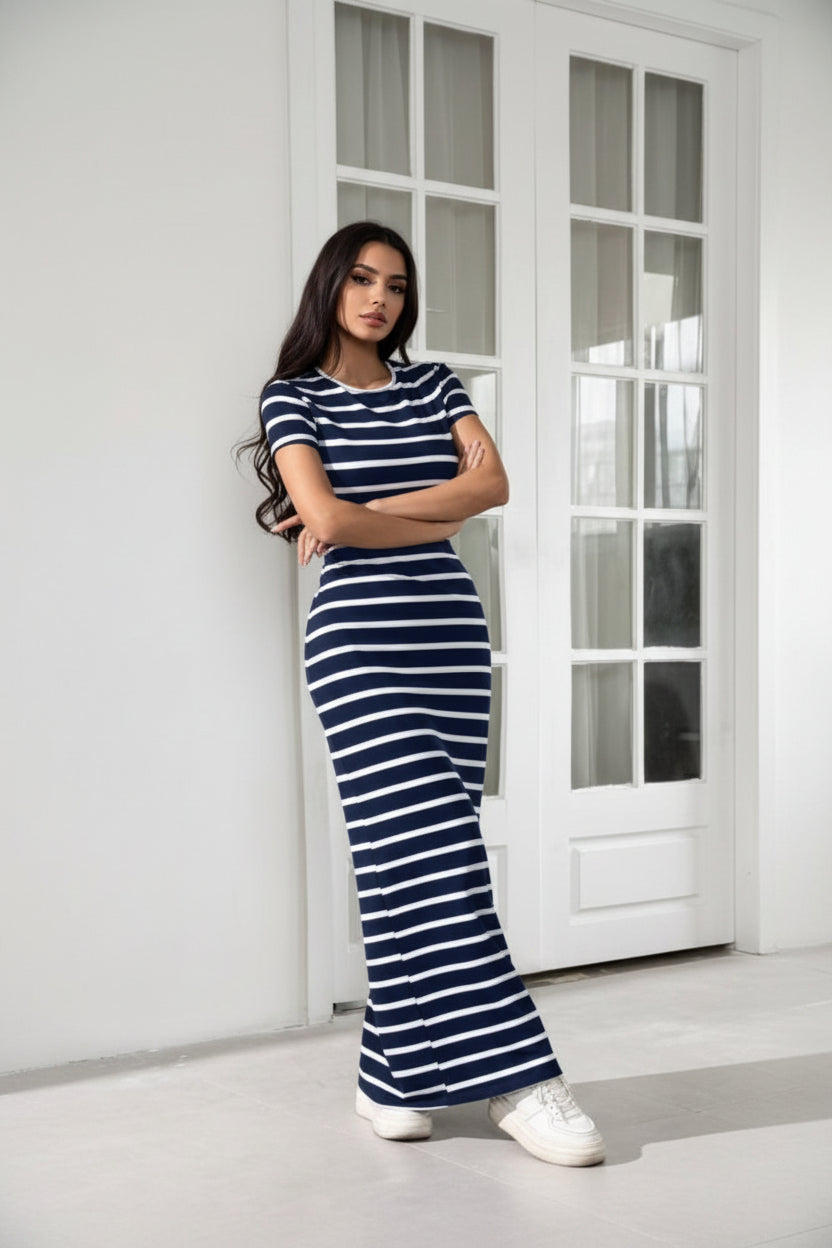 Person wearing a navy and white striped outfit with wide-leg pants in a minimal indoor setting.