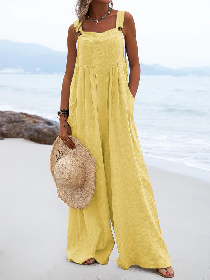 Woman in a yellow dress holding a straw hat on a beach