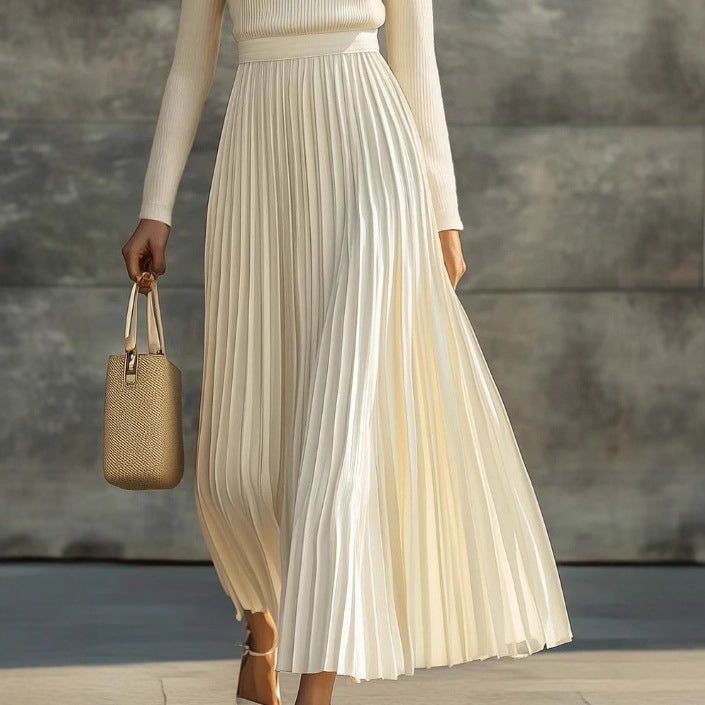 Woman wearing a beige pleated skirt holding a woven handbag against a neutral background