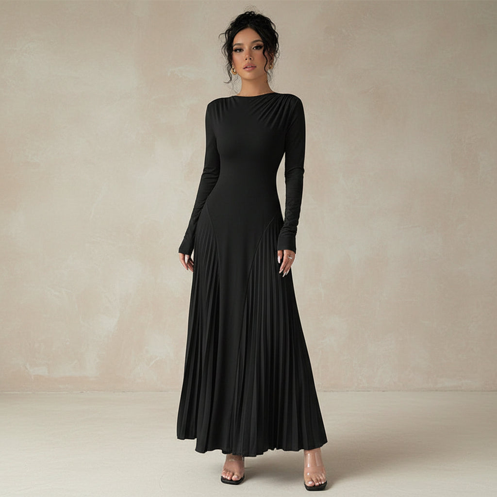 Woman wearing a black long-sleeve dress holding a clear handbag against a neutral background