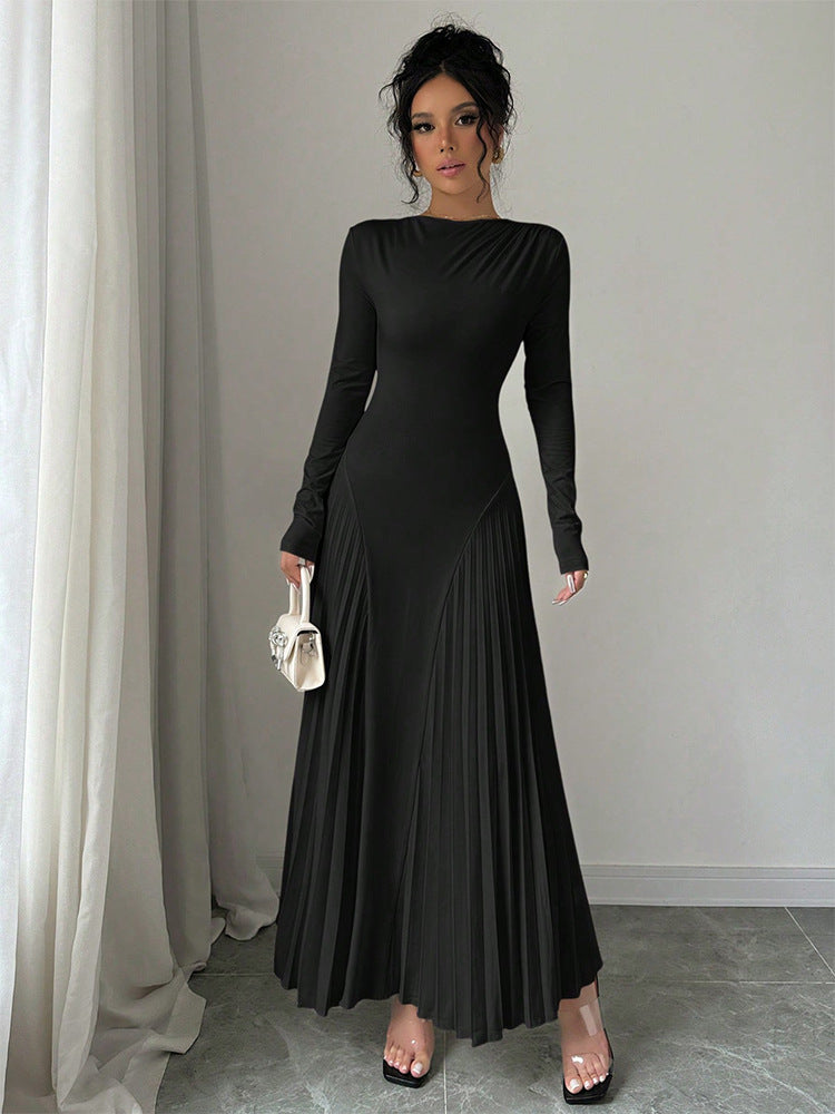 Woman wearing a black long-sleeve dress holding a clear handbag against a neutral background