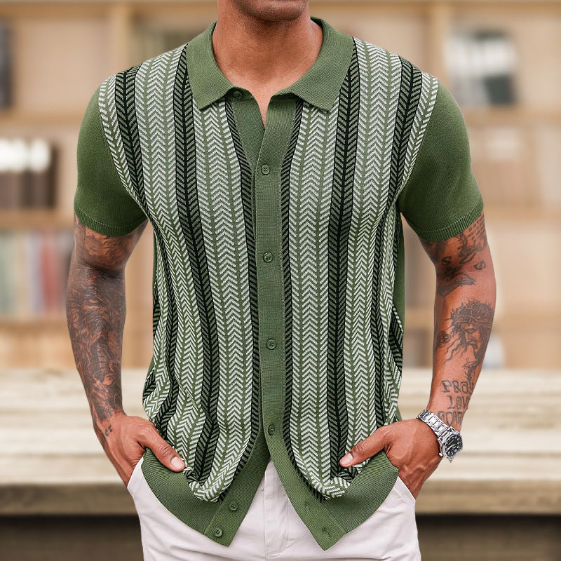 Man wearing a green patterned vest over a shirt with tattoos on arms, blurred background