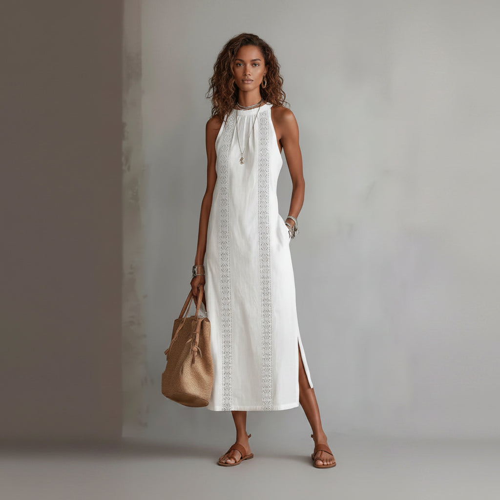 Woman wearing a white dress with lace details and holding a beige handbag against a gray background