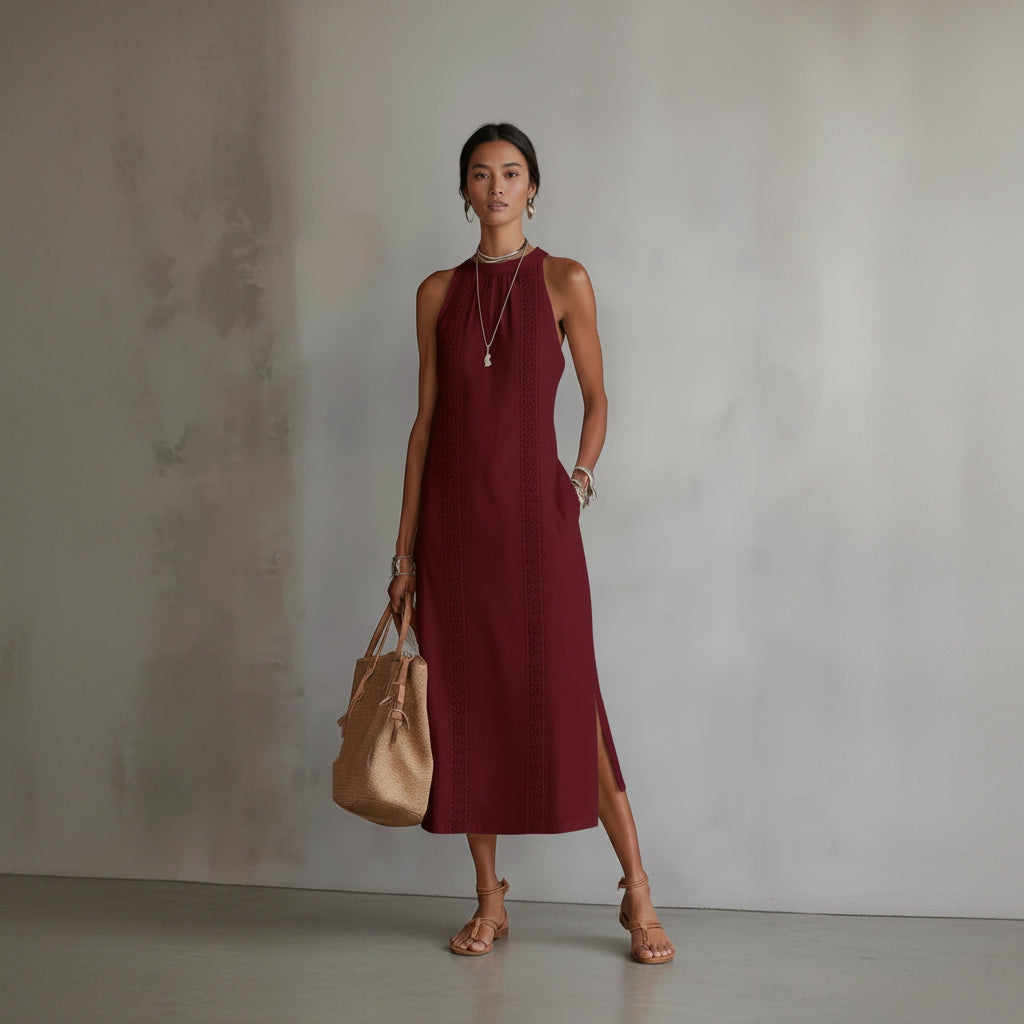 Woman wearing a burgundy dress holding a beige handbag against a neutral background