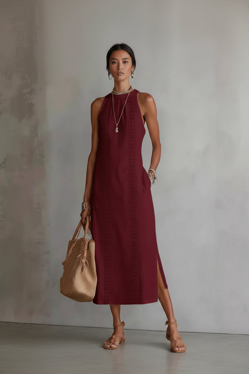 Woman wearing a burgundy dress holding a beige handbag against a neutral background