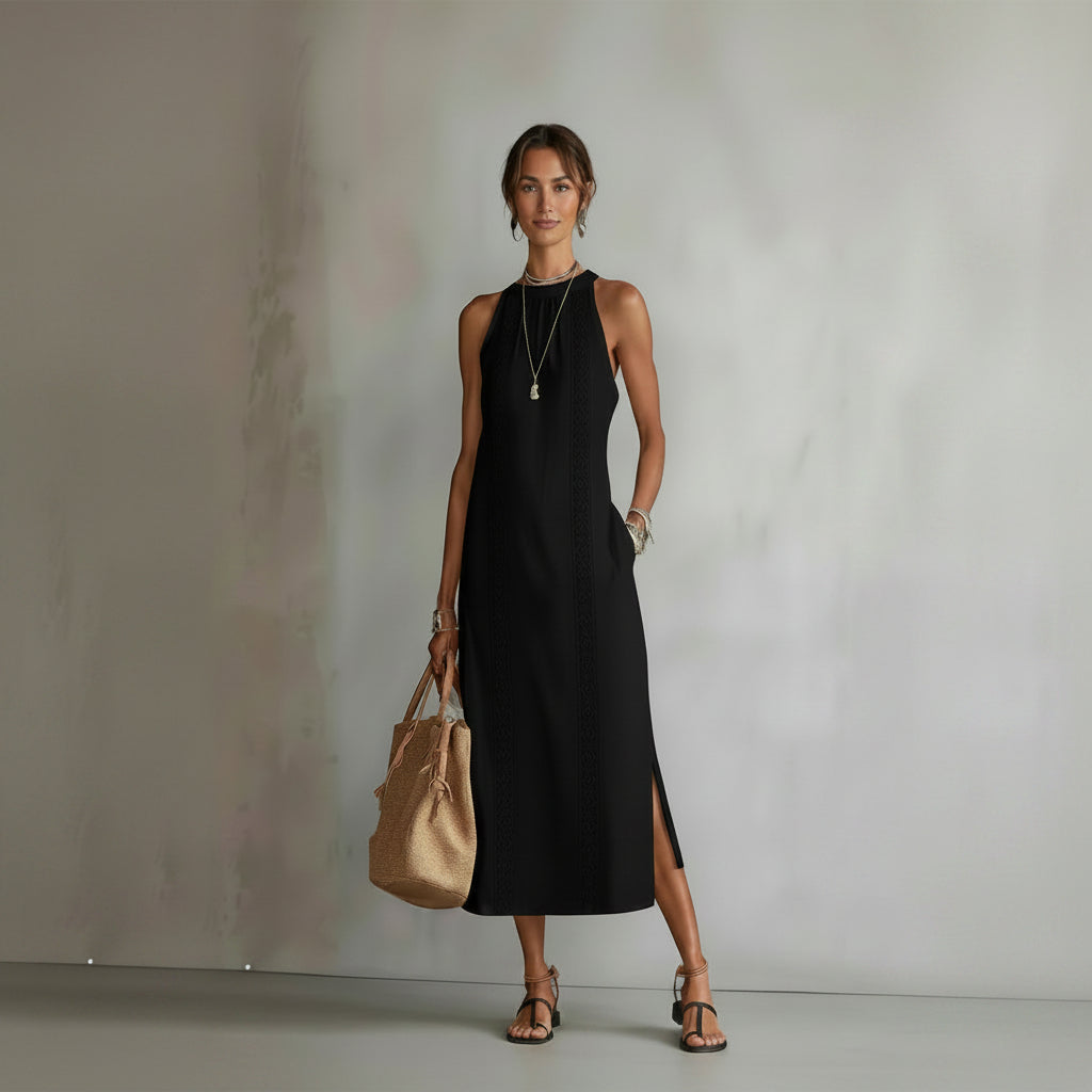 Woman wearing a black sleeveless dress holding a beige handbag against a neutral background
