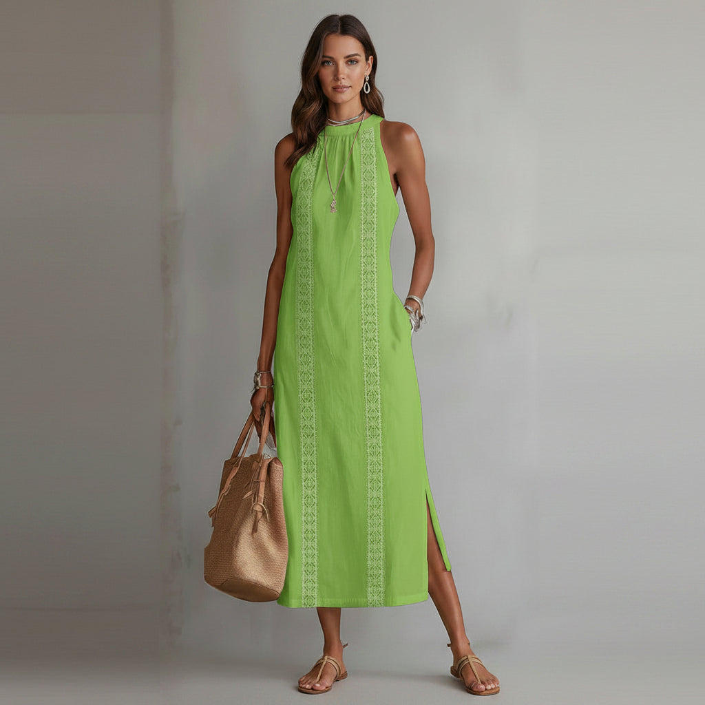 Green dress with white patterns worn by a person, holding a beige handbag against a neutral background