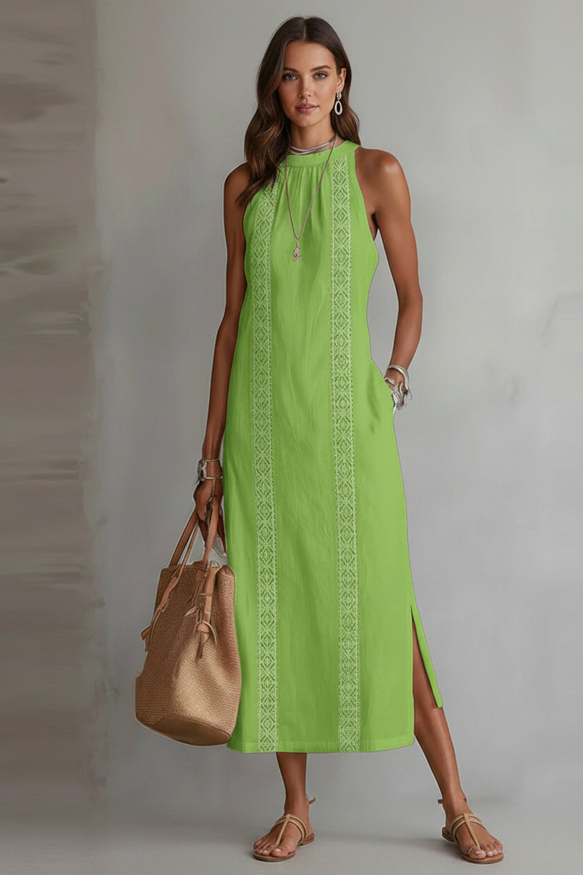 Green dress with white patterns worn by a person, holding a beige handbag against a neutral background
