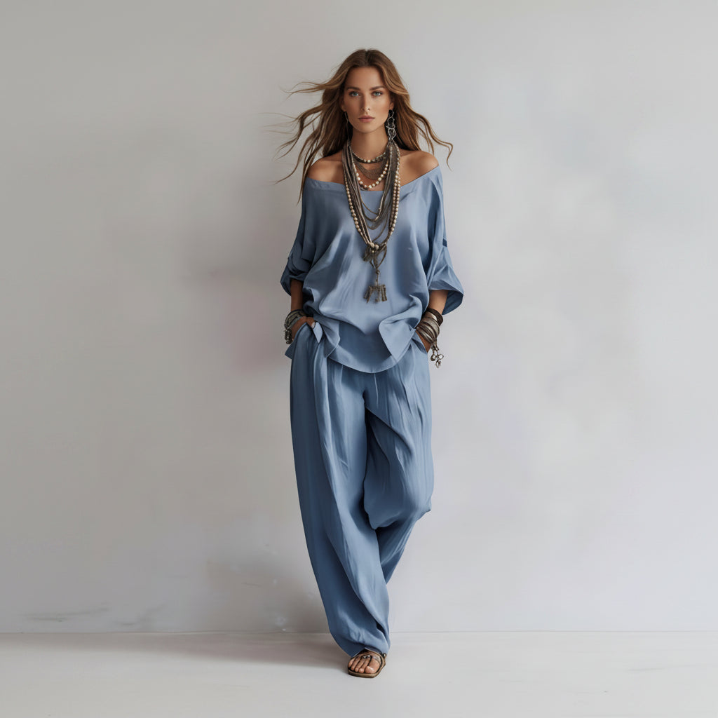Woman wearing a blue outfit with wide-leg pants and off-shoulder top on a plain background