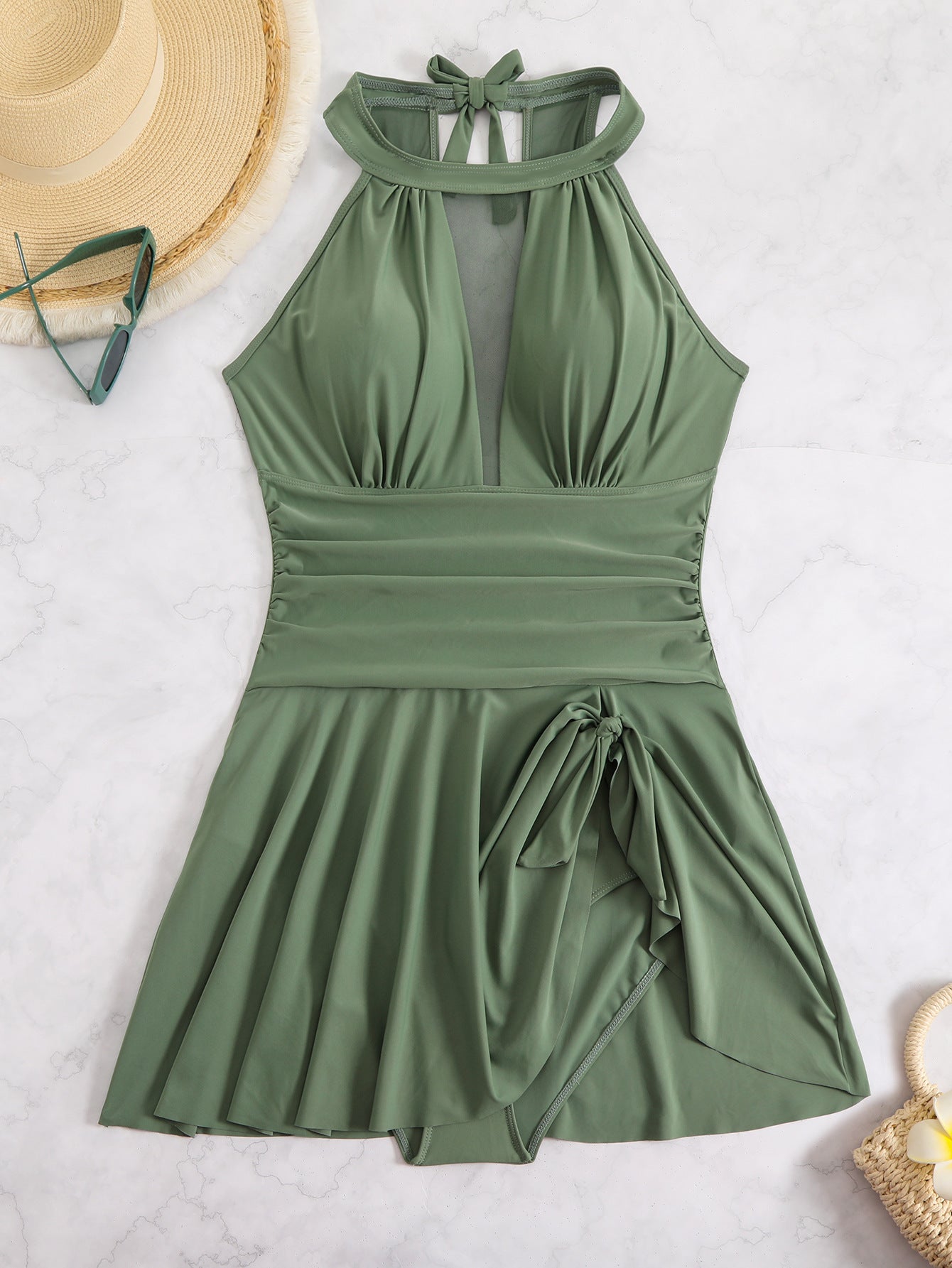 Green halter neck dress with a bow detail on a light gray background