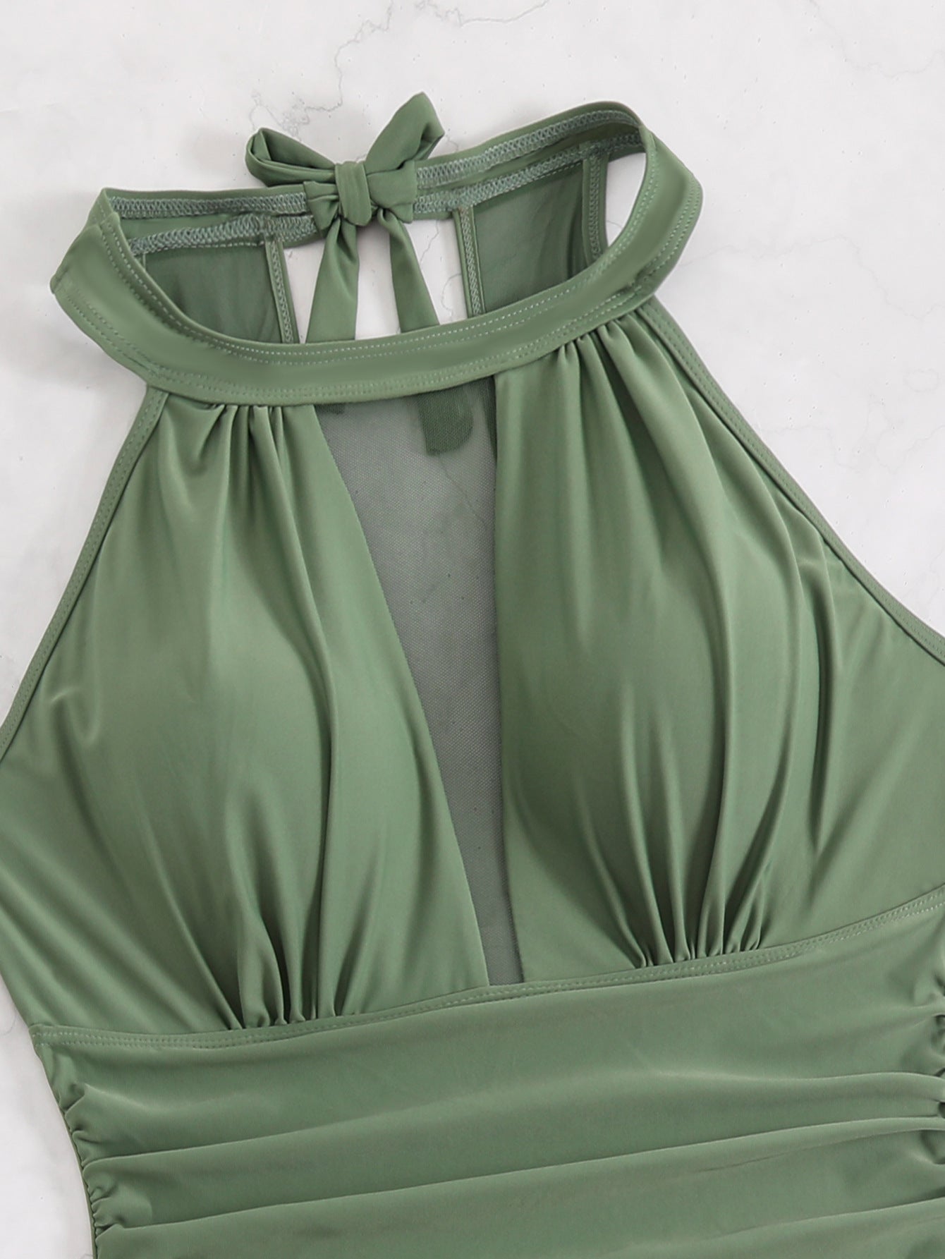 Green halter top with a bow detail on a white background