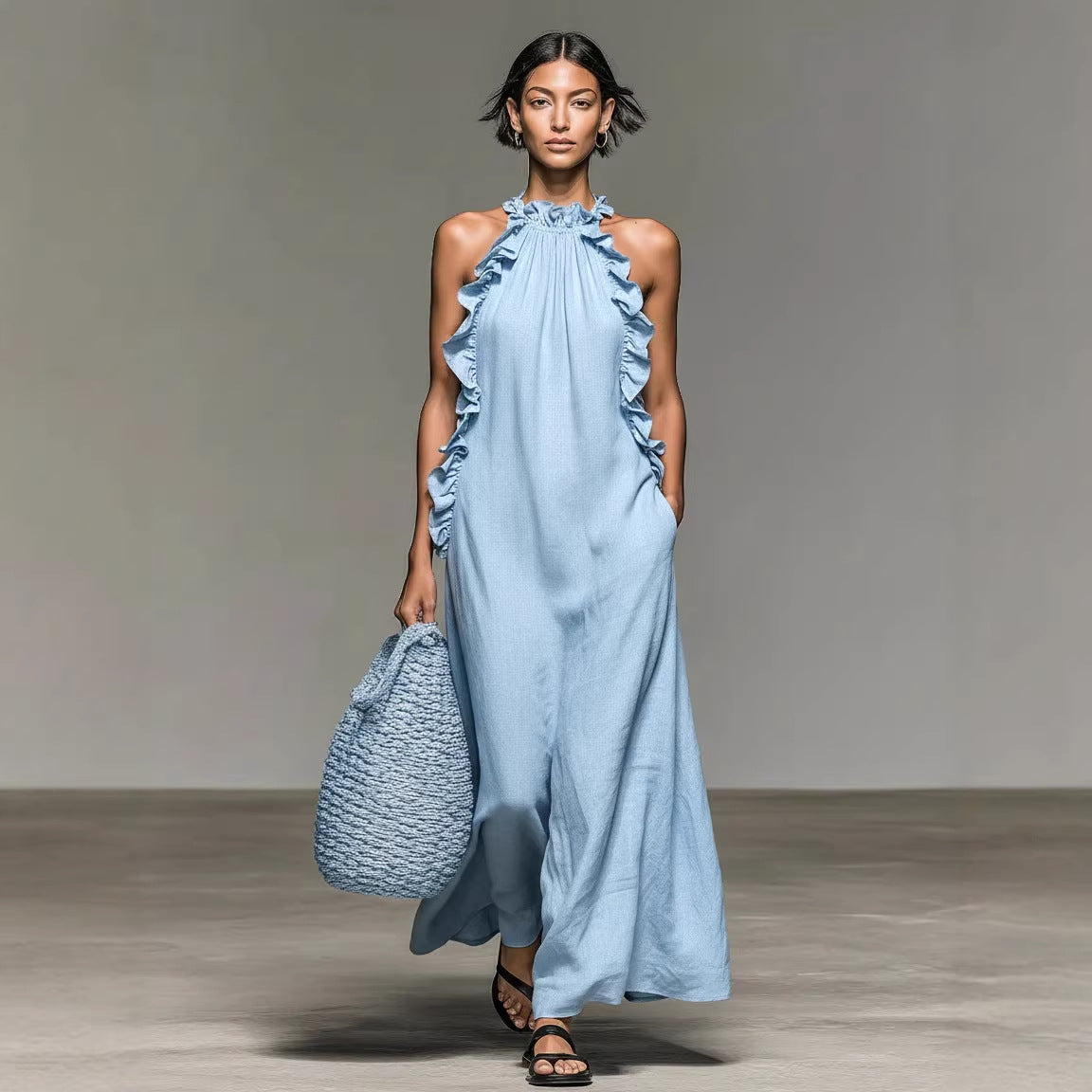 Woman wearing a light blue dress with ruffled details, holding a matching bag on a plain background.