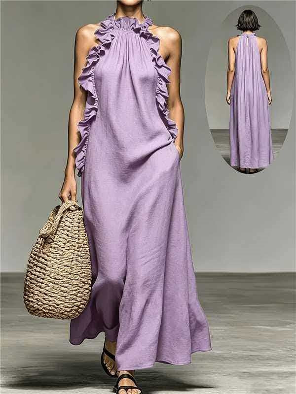Woman wearing a long purple dress holding a woven bag on a gray background