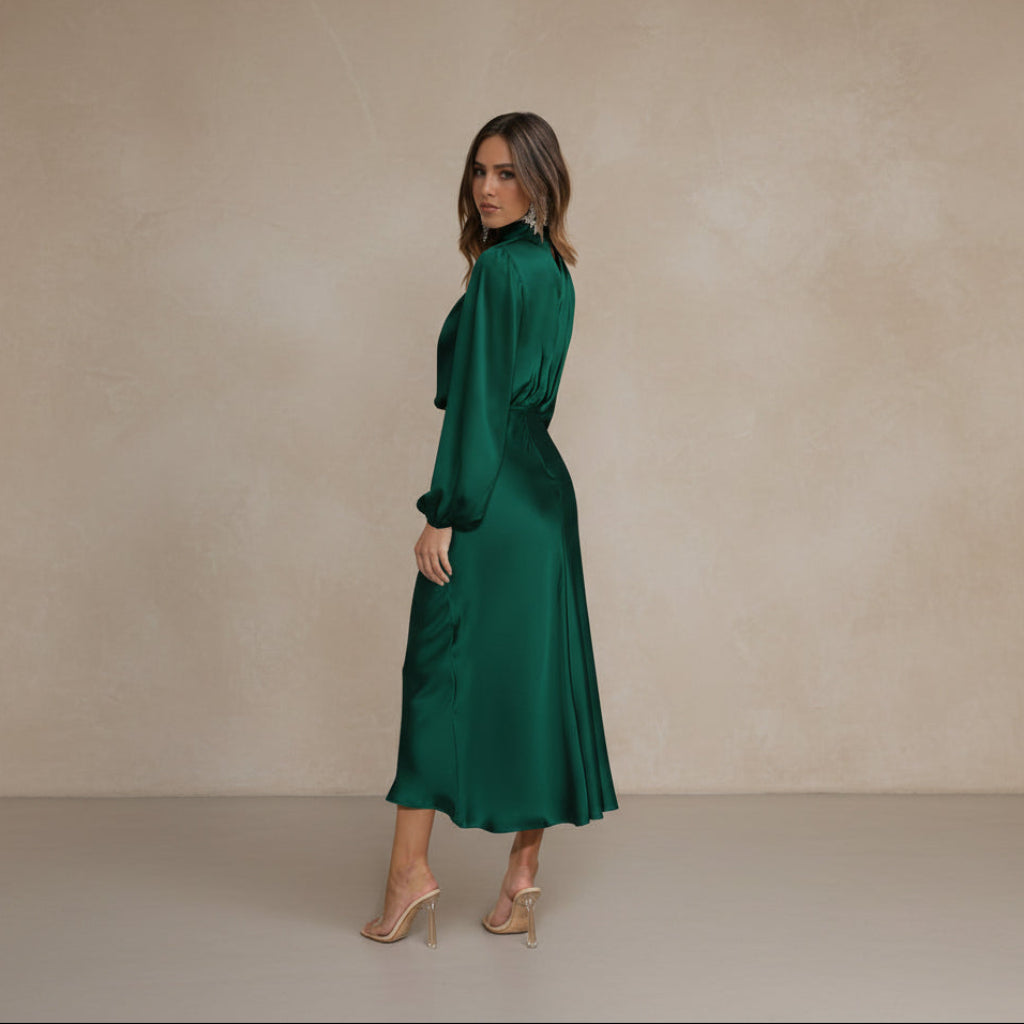 Woman wearing a green satin dress in a minimalistic room.