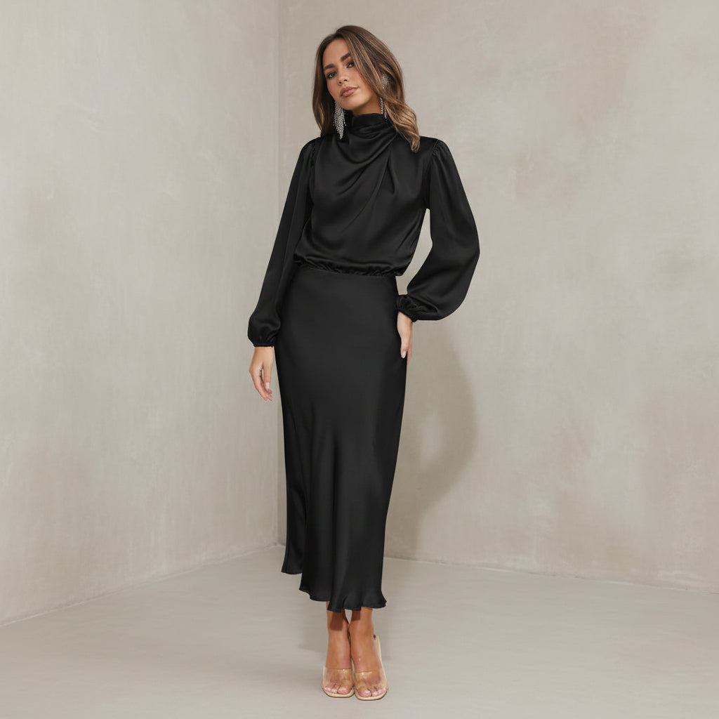 Woman wearing a black outfit standing in a minimalistic room.