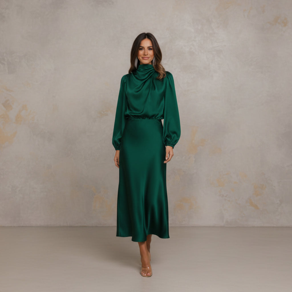 Woman wearing a green dress standing in a minimalistic room.