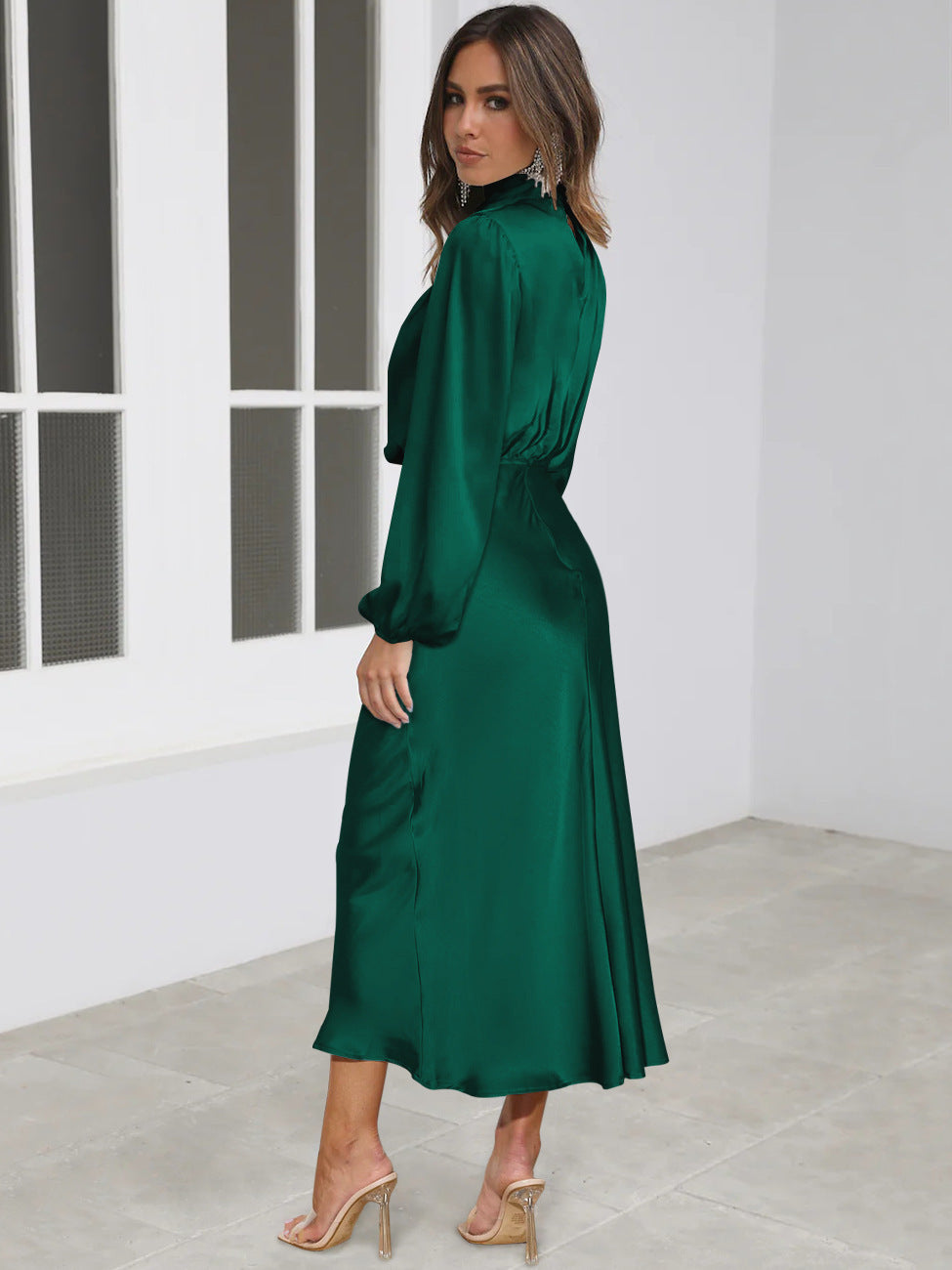 Woman wearing a green satin dress in a minimalistic room.