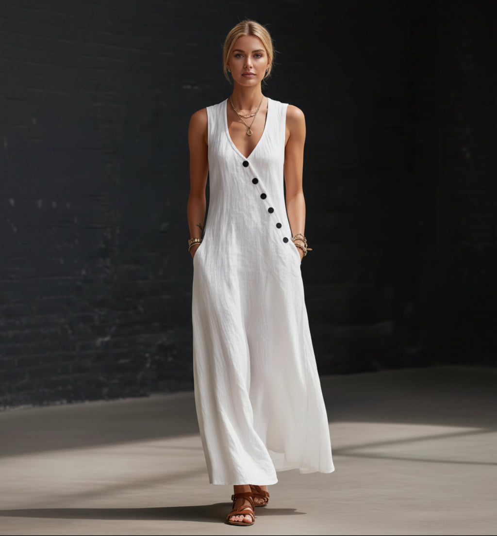 Woman wearing a white sleeveless dress with black buttons against a dark background