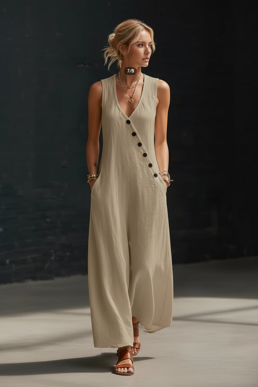 Woman wearing a beige sleeveless dress with black buttons against a dark background