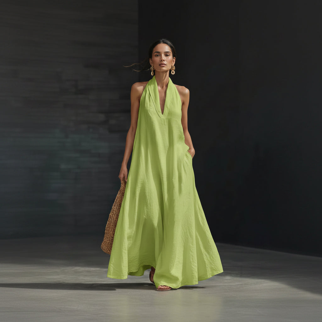 Woman wearing a bright green dress holding a woven bag against a dark background