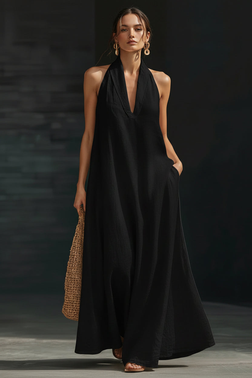 Woman wearing a black halter neck dress holding a woven bag against a dark background