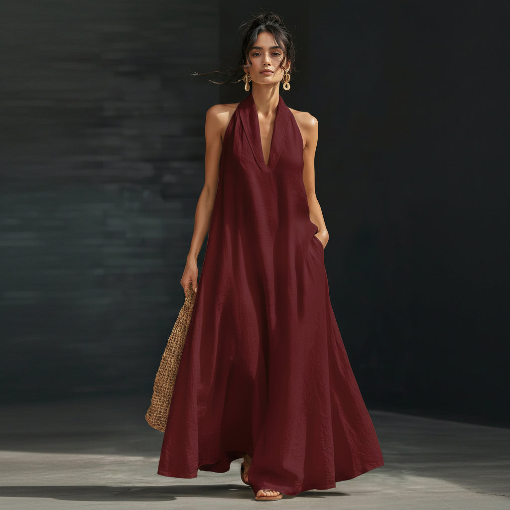 Woman wearing a burgundy halter neck dress against a dark background