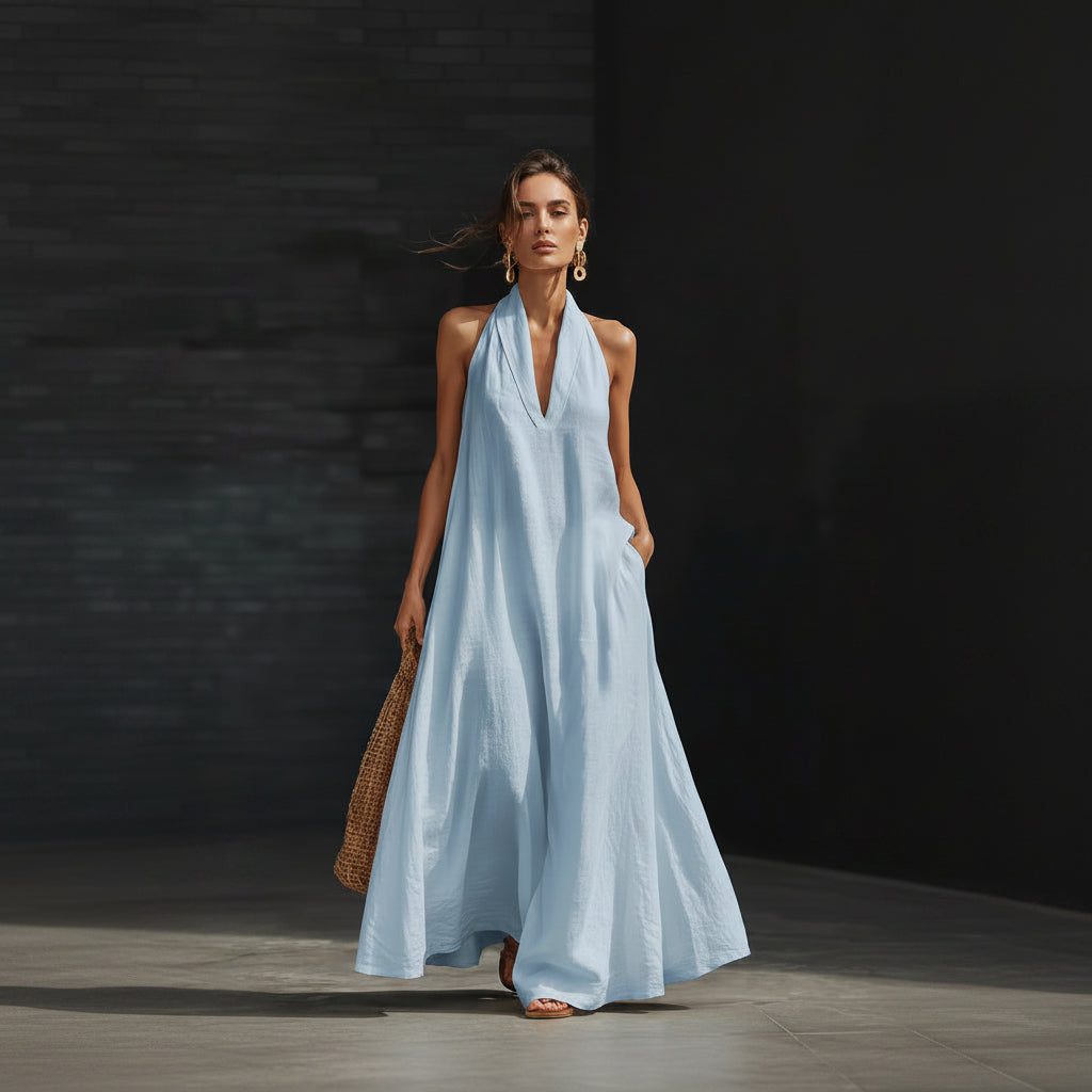 Woman wearing a light blue halter neck dress against a dark background