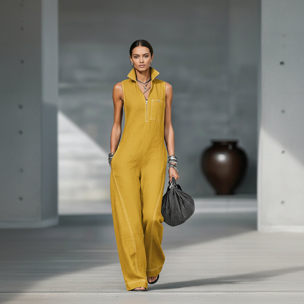 Person wearing a mustard yellow sleeveless jumpsuit holding a black handbag.