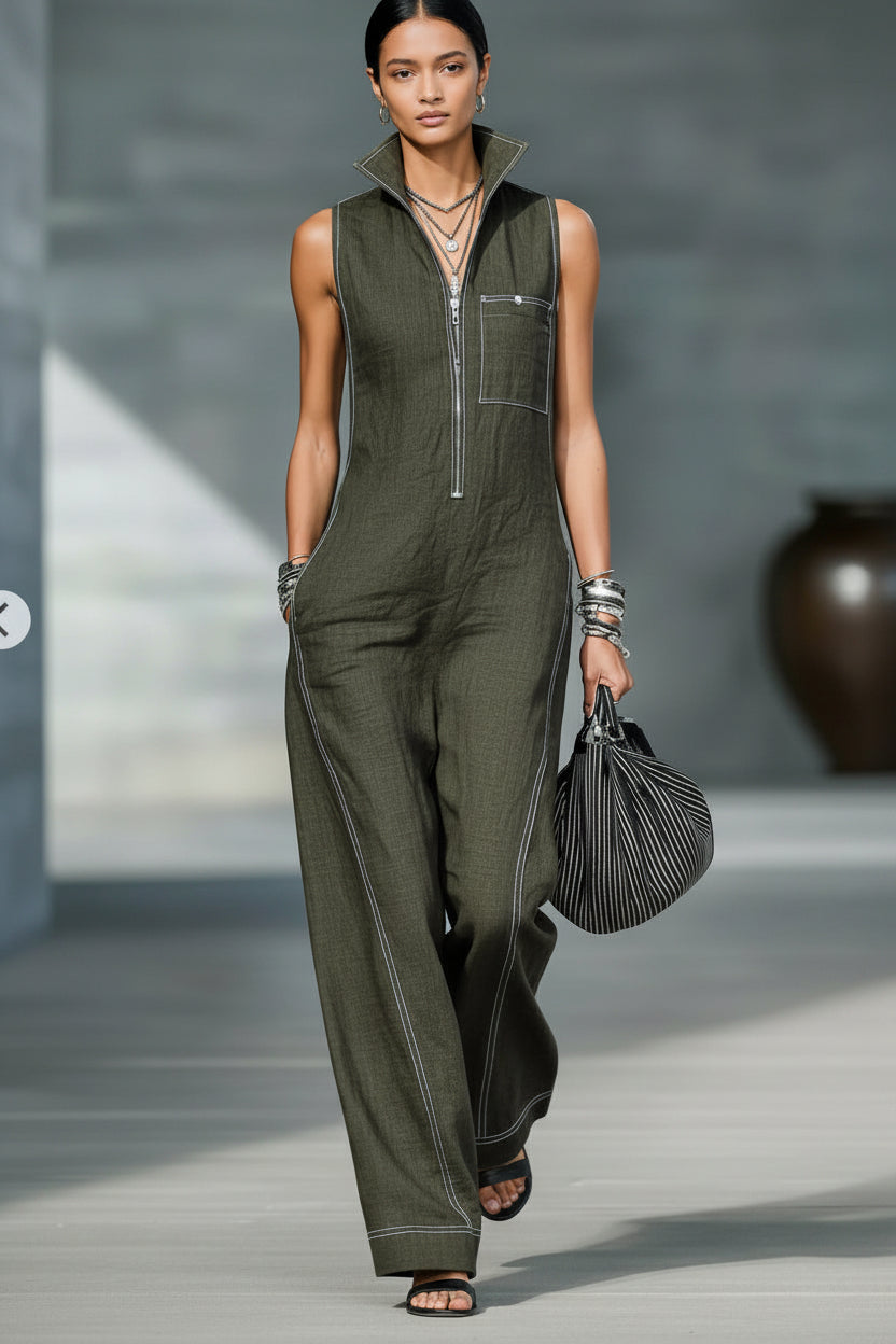 Woman wearing a green jumpsuit holding a black handbag against a neutral background