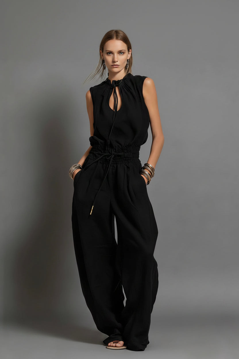 Black jumpsuit worn by a model on a gray background