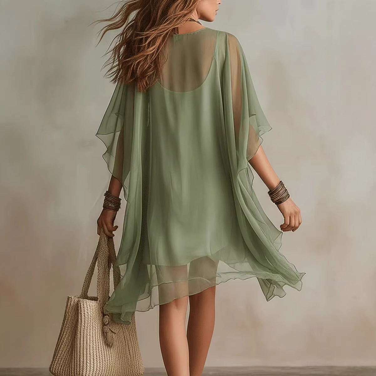 Woman wearing a light green sheer dress holding a woven bag against a neutral background