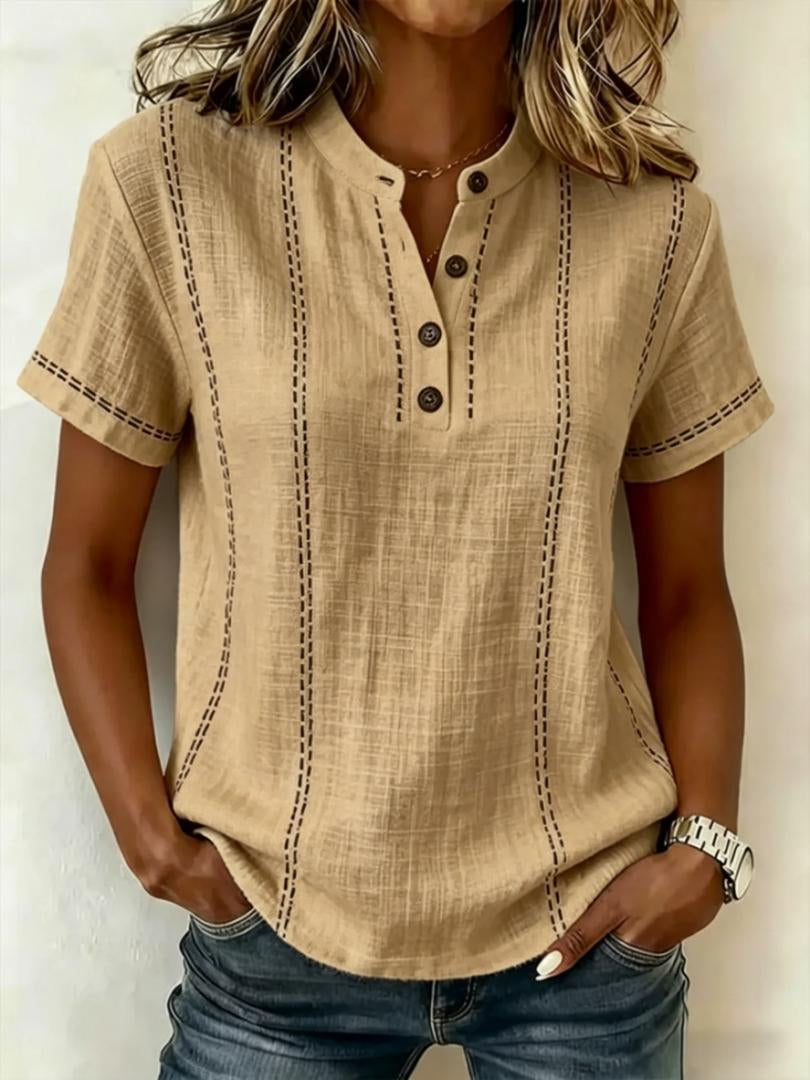 Person wearing a beige short-sleeve shirt with black stitching on a plain background