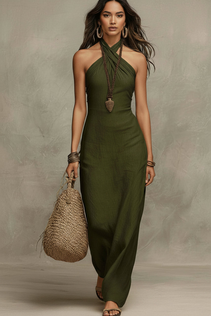 Woman wearing a green halter neck dress holding a woven bag against a neutral background