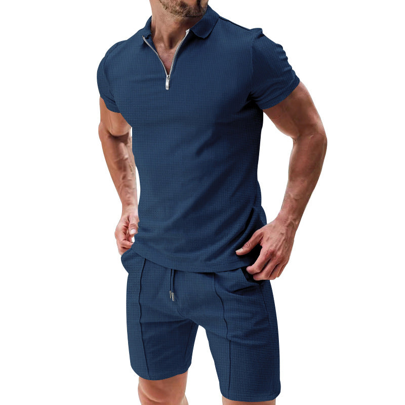 Man wearing a navy blue polo shirt and shorts set on a white background