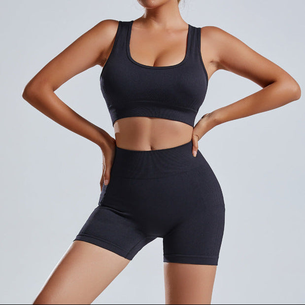 Woman wearing a black sports bra and shorts on a light gray background