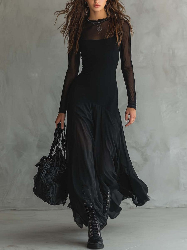 Person wearing a long black dress with sheer sleeves against a gray background