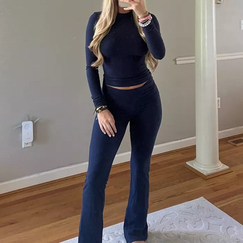 Person wearing a navy blue outfit in a room with wooden flooring and gray walls.