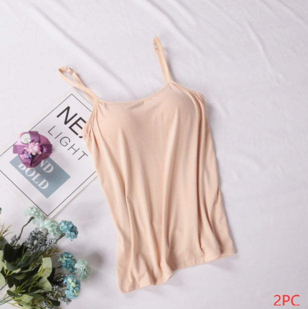 Beige camisole on a white surface with a magazine and flowers.