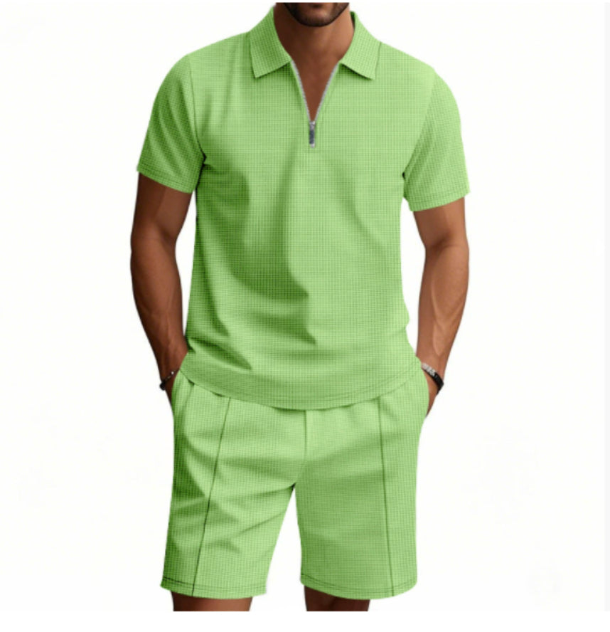 Person wearing a matching green polo shirt and shorts set on a white background