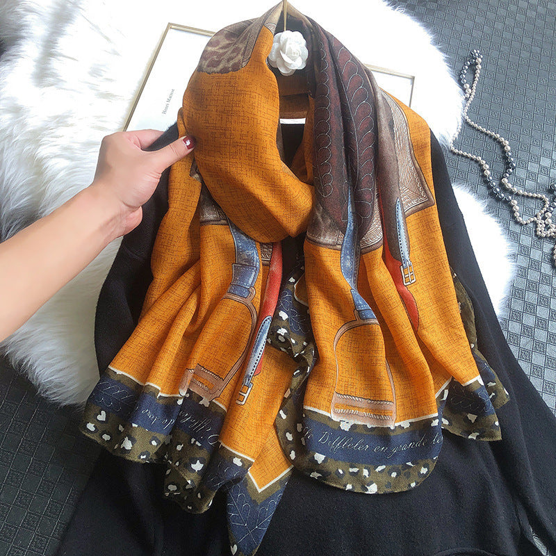 Orange scarf with pattern held by a hand against a dark background