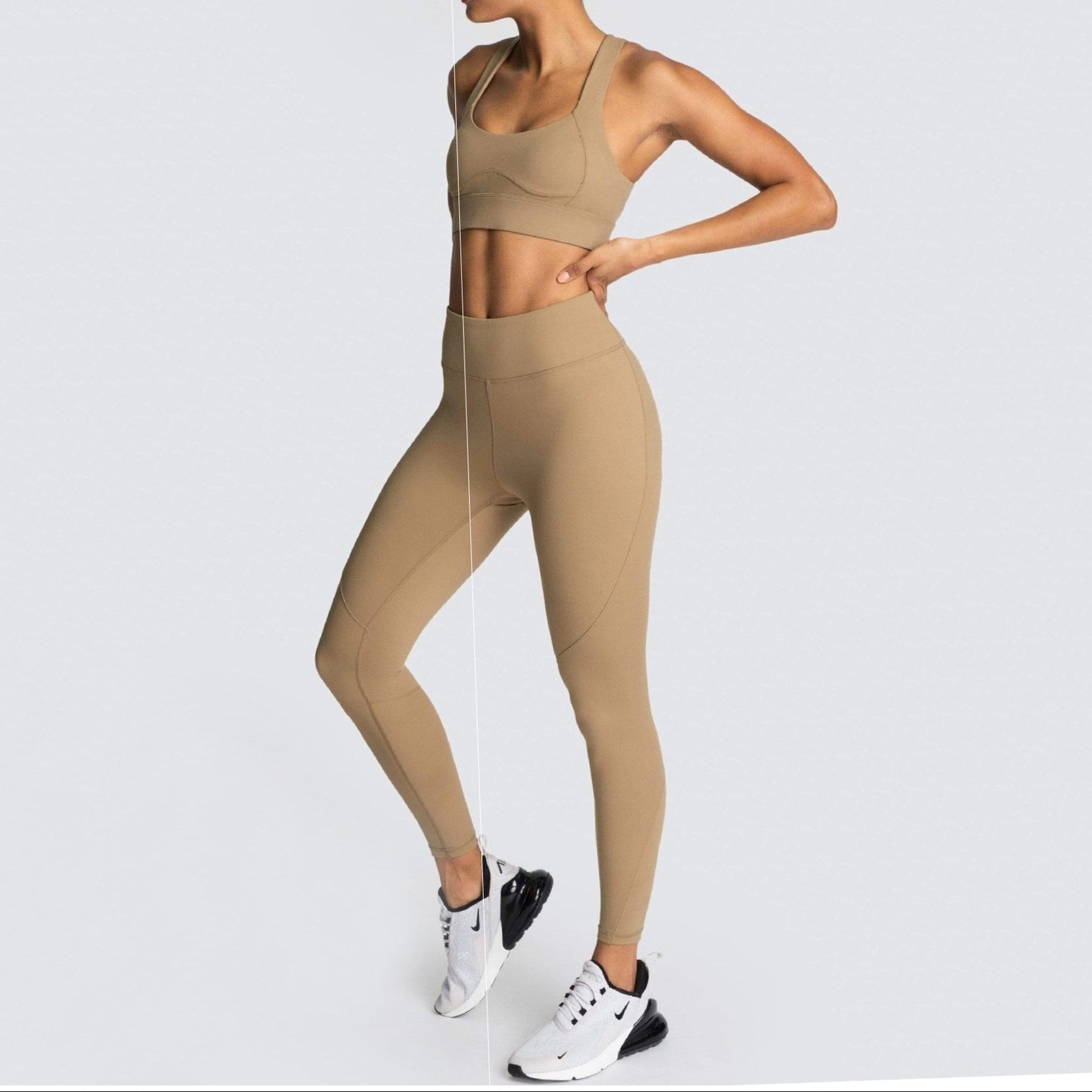 Woman wearing a beige sports bra and leggings set on a light gray background