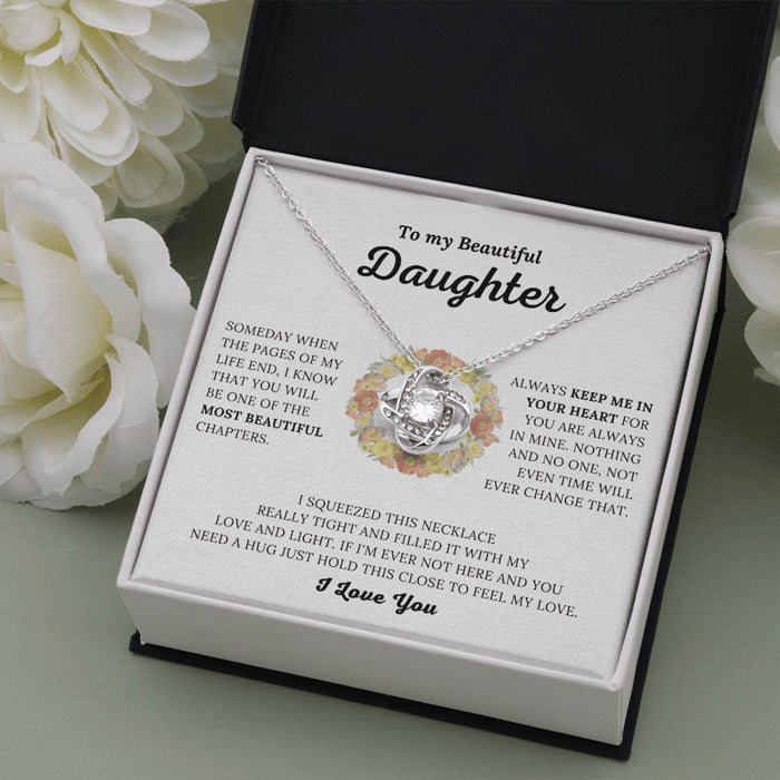 Necklace with a message card for a daughter, surrounded by flowers.